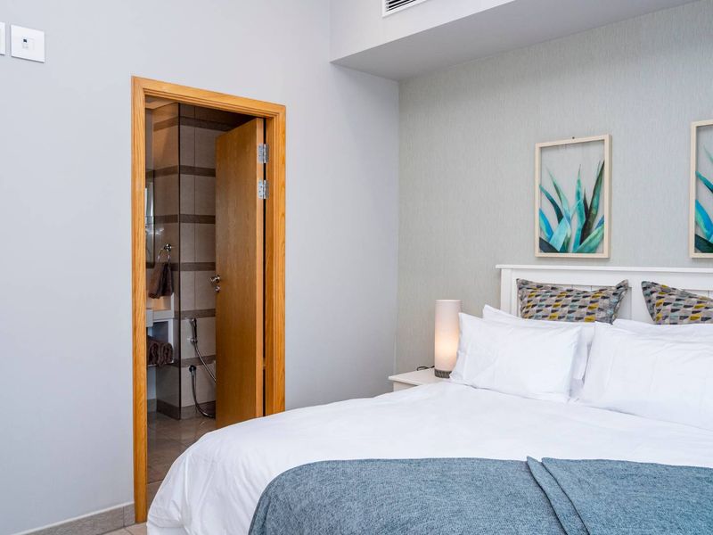 A well-maintained bedroom featuring textured wallpaper, an air conditioning vent, and direct access to an en-suite bathroom.