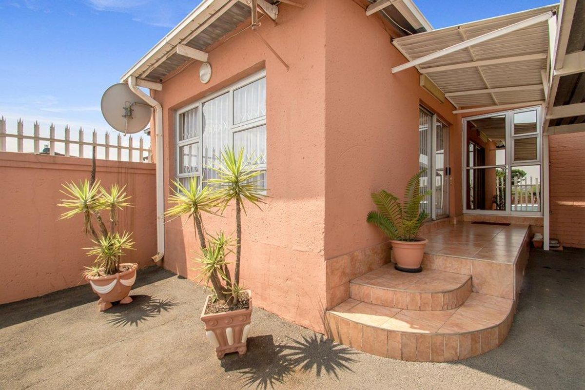 Exterior view of the property featuring a paved patio area, tiled entrance steps, and a covered walkway leading to the main entrance.