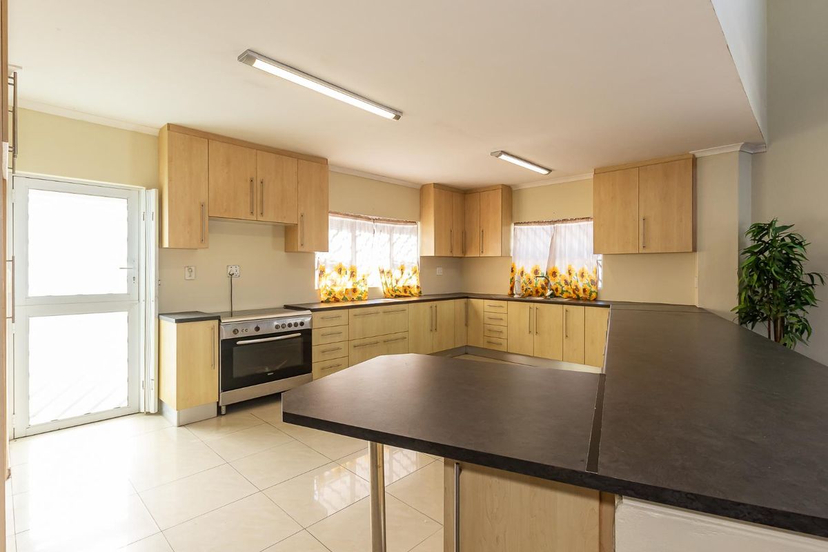 Spacious kitchen featuring light wood cabinetry, dark laminate countertops, a freestanding oven, and tiled flooring with ample workspace.