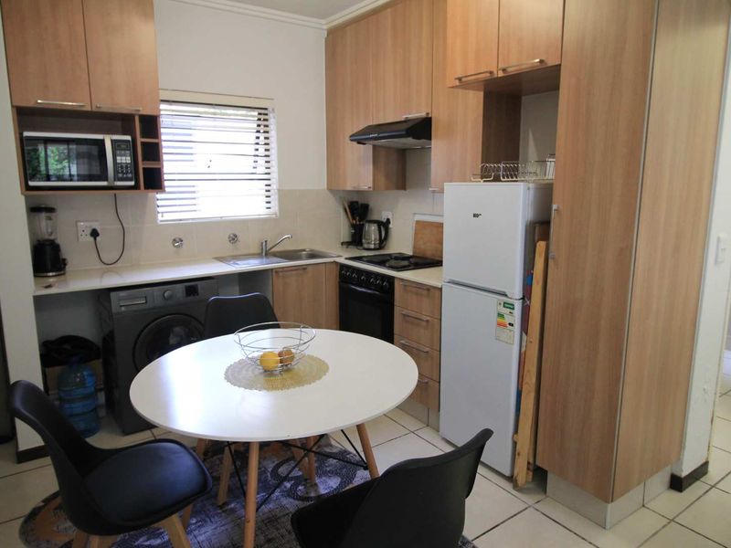 Compact kitchen featuring light wood-finish cabinetry, laminate countertops, integrated appliances, and tiled flooring, providing a functional and efficient cooking and dining space.