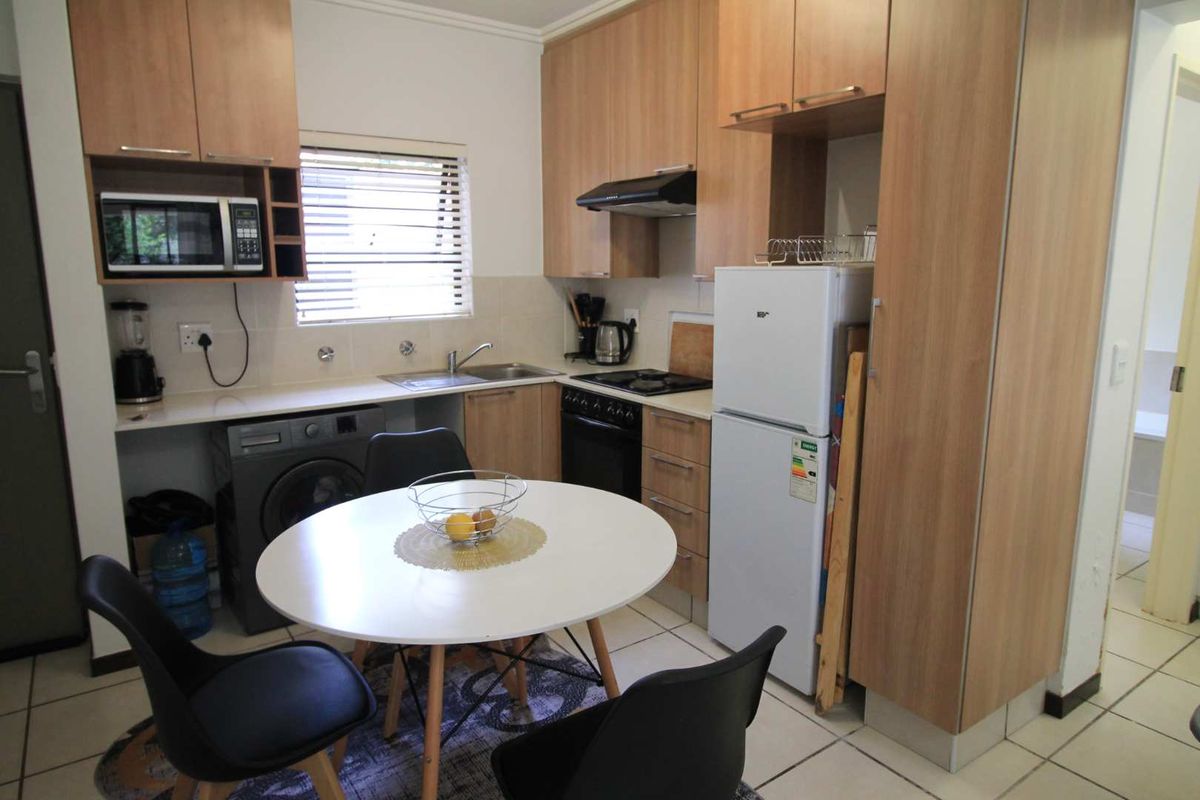 Compact kitchen featuring light wood-finish cabinetry, laminate countertops, integrated appliances, and tiled flooring, providing a functional and efficient cooking and dining space.
