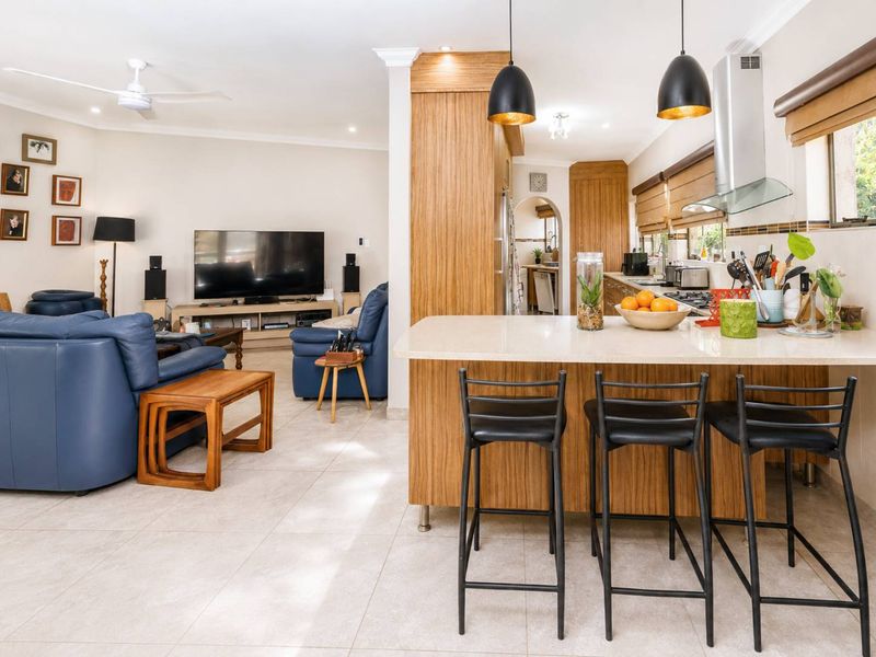 Spacious open-plan living area featuring a modern kitchen with stone countertops, a central island, and seamless flow into the comfortable lounge space.