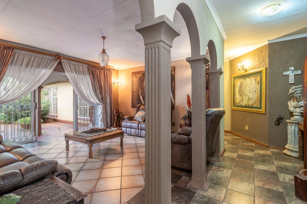 Spacious living area featuring decorative arched columns, tiled flooring, and sliding glass doors providing seamless access to the covered patio.