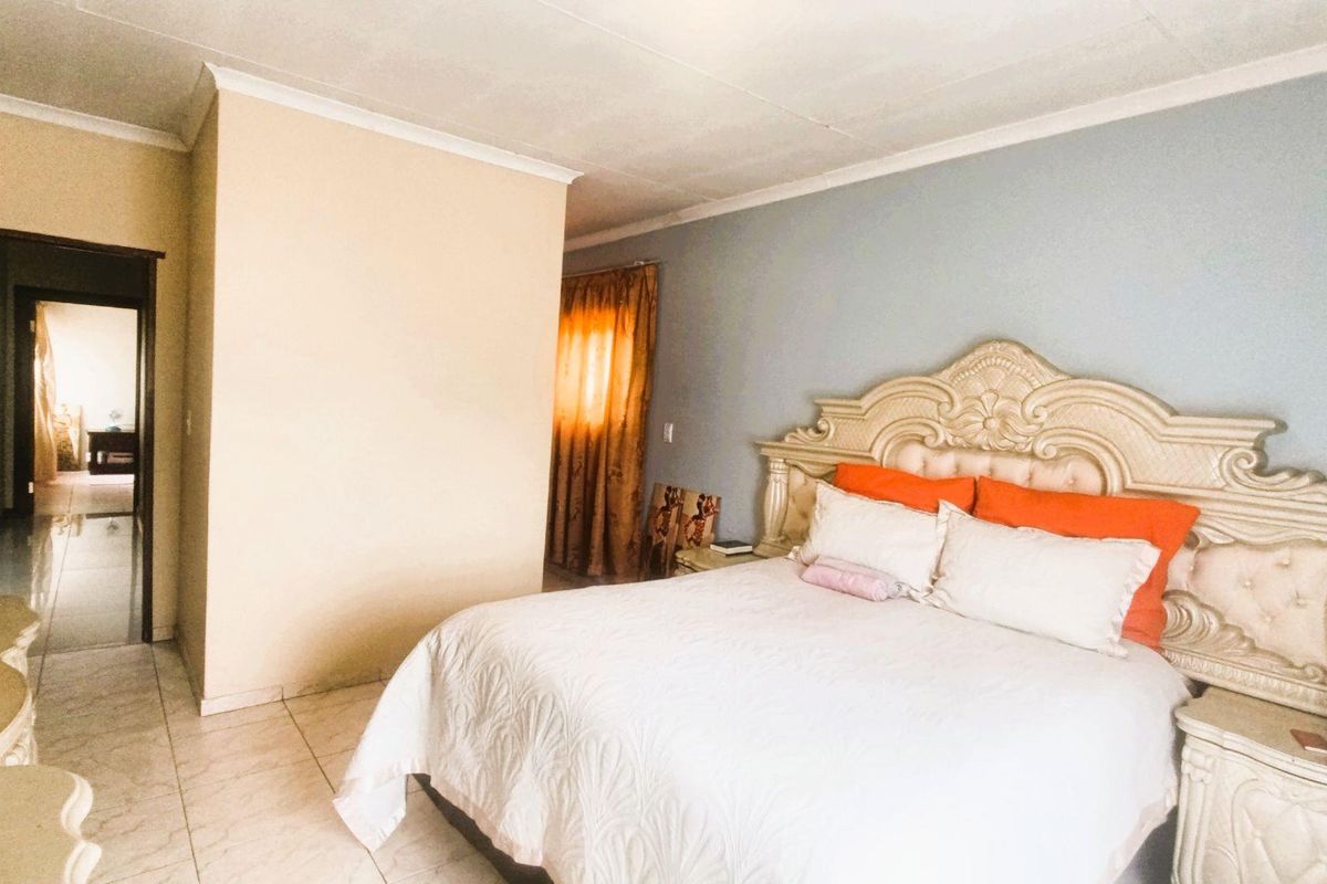 A spacious bedroom featuring tiled flooring, coved ceilings, and a neutral color palette, providing a functional and comfortable sleeping area.