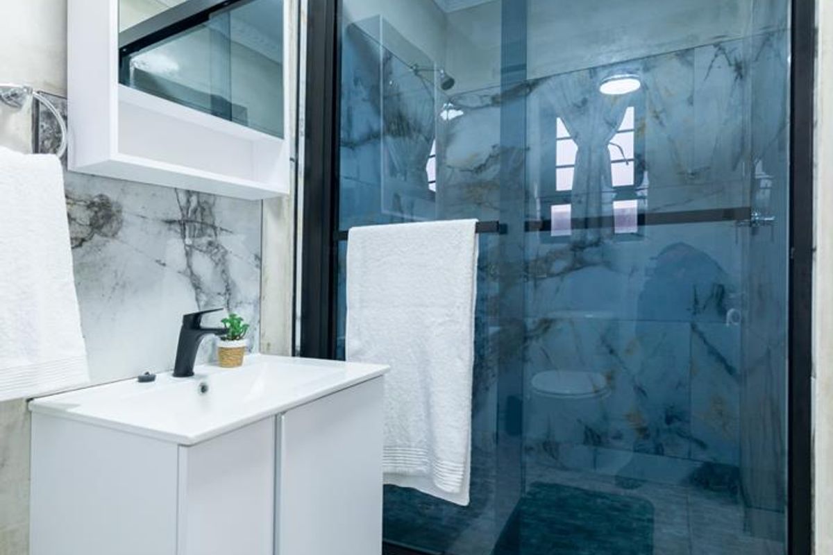 Modern bathroom featuring a sleek vanity, marble-look wall tiling, and a contemporary glass-enclosed shower with black framing.