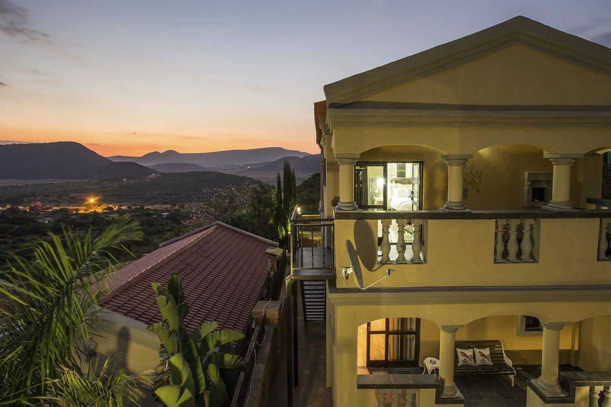 Rear view of the guest house featuring multi-level balconies and patios with scenic mountain views at sunset.
