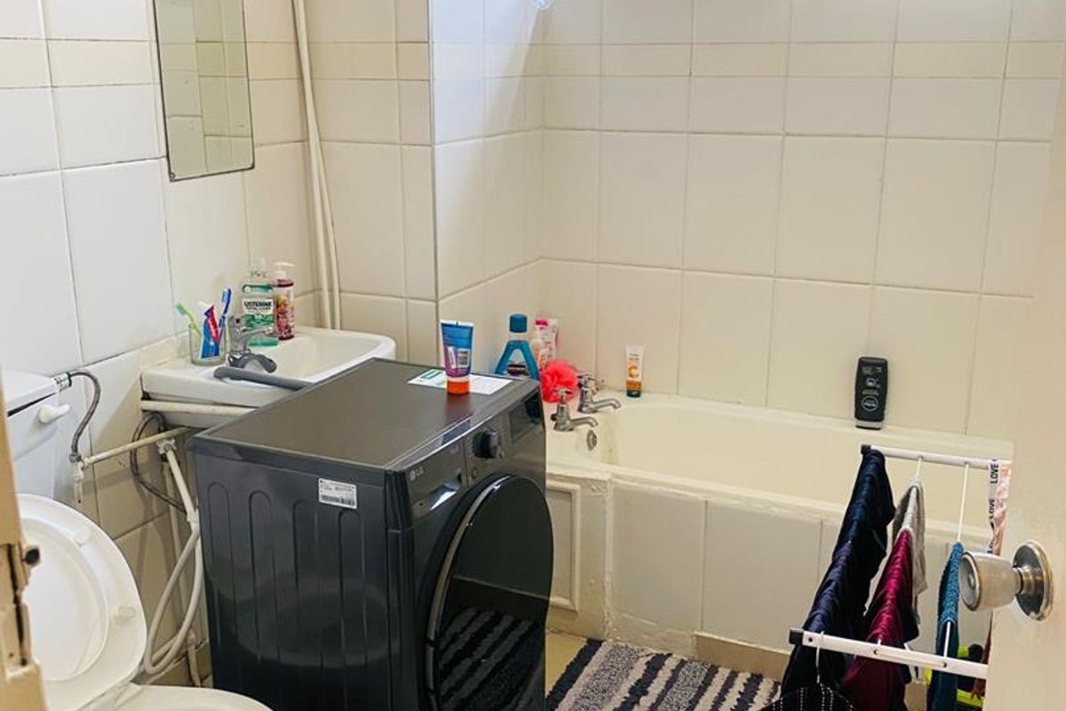 A functional bathroom featuring a bathtub, toilet, and washbasin with tiled finishes, requiring cosmetic updates to improve the overall aesthetic and condition.