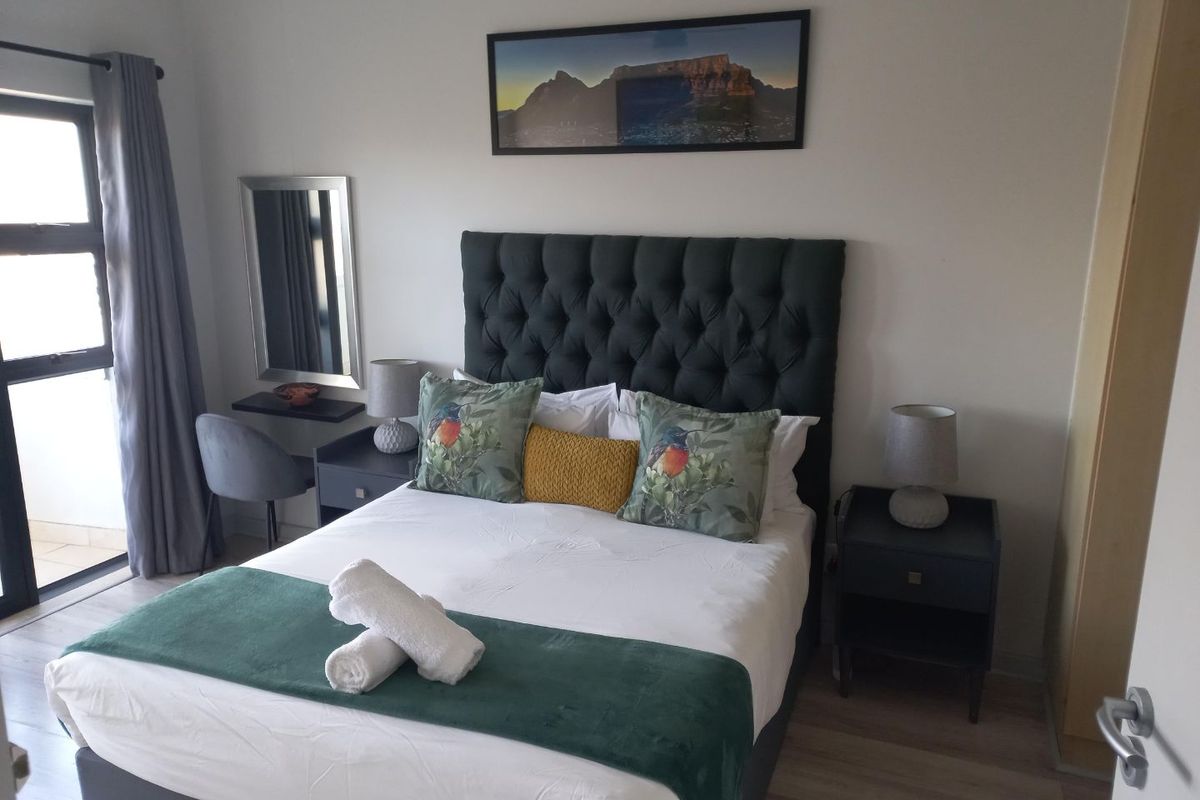 A well-maintained bedroom featuring laminate flooring, a sliding door providing natural light, and a built-in vanity area.