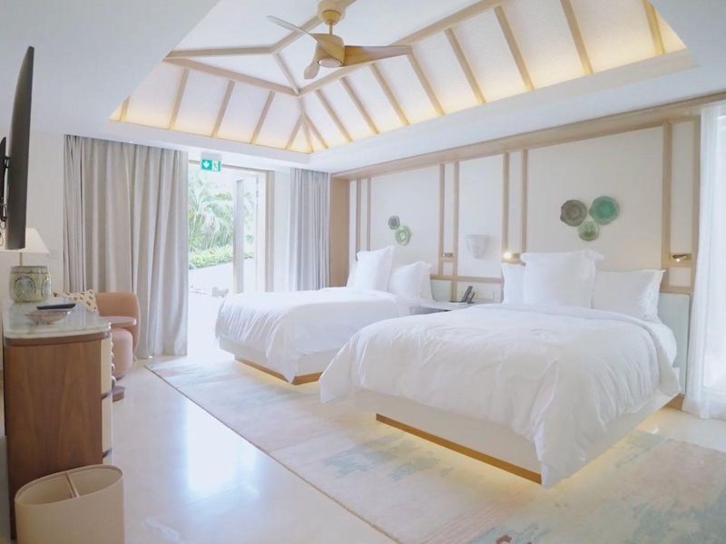 Spacious bedroom featuring a vaulted ceiling with integrated lighting, ceiling fan, and direct access to an outdoor area through glass doors.