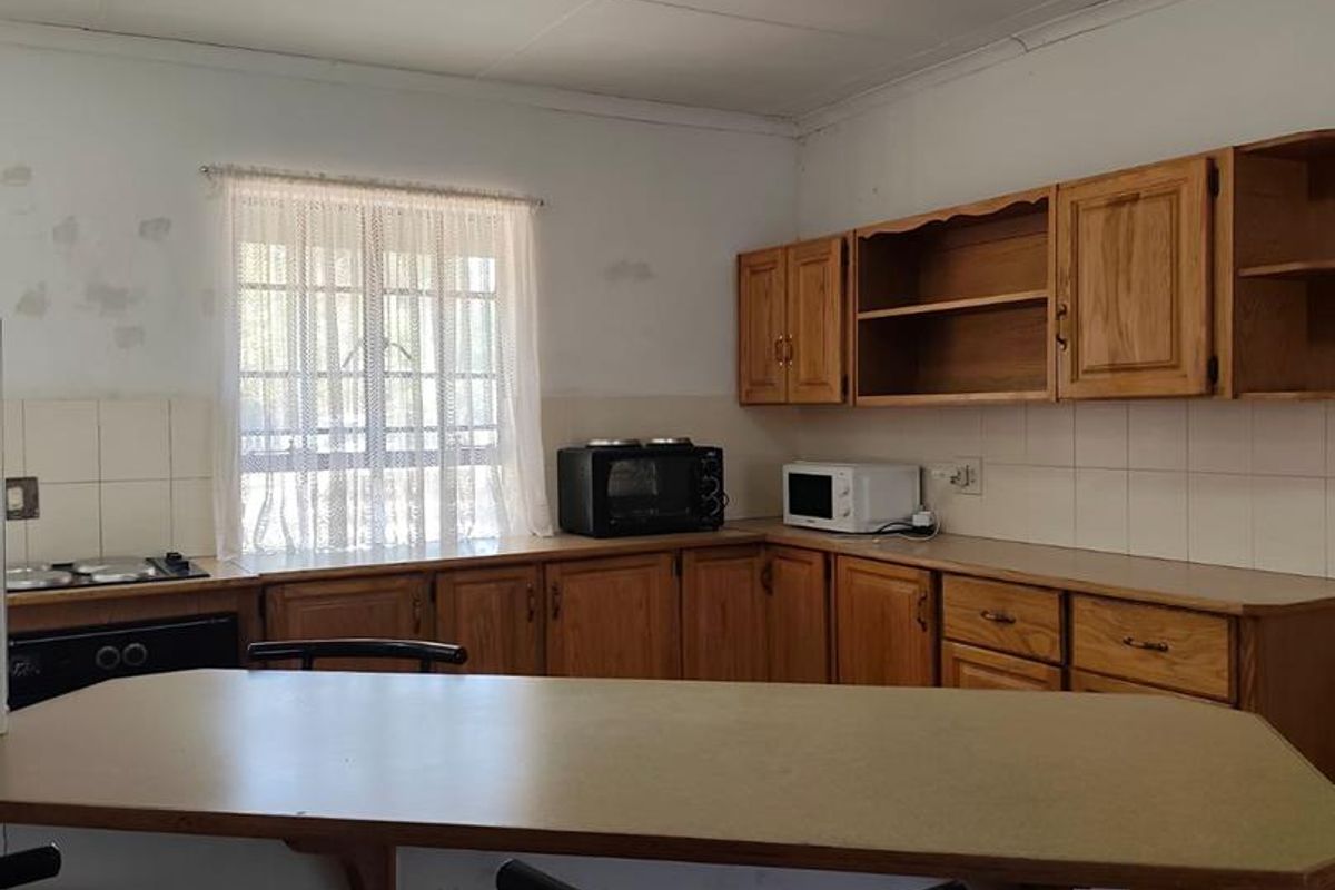 A dated kitchen featuring wooden cabinetry, laminate countertops, and a breakfast bar, requiring cosmetic updates to improve the overall aesthetic and condition.