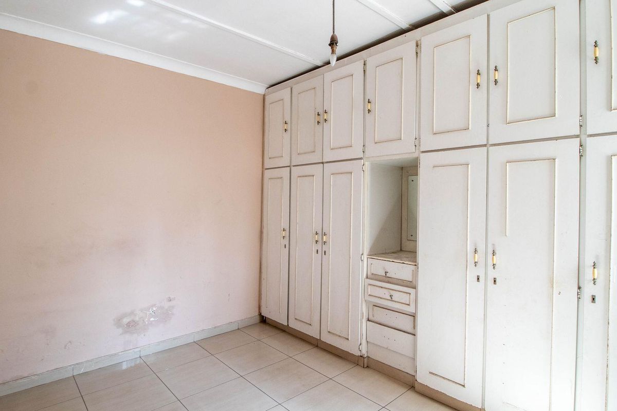 A bedroom featuring extensive built-in floor-to-ceiling cabinetry with integrated vanity drawers and tiled flooring.