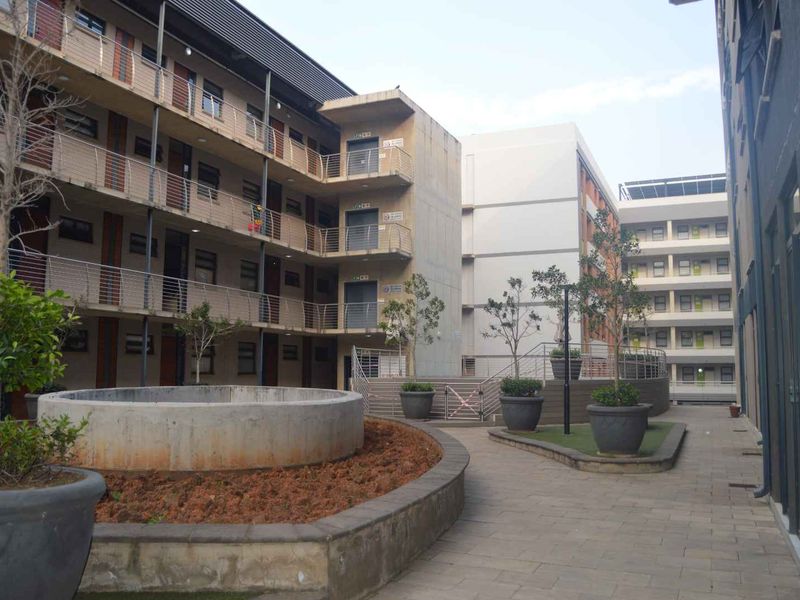 A view of the apartment complex courtyard featuring paved walkways, concrete planters, and multi-story residential building facades with external access balconies.