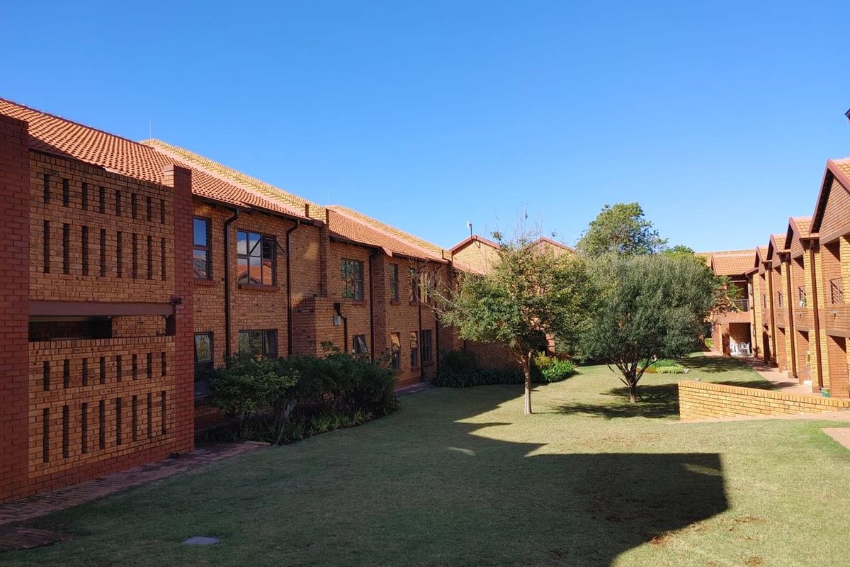 A well-maintained exterior view of the retirement village featuring face brick buildings, terracotta roofing, and established garden areas with mature trees.