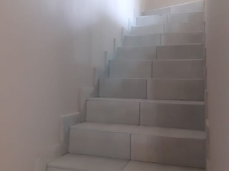A simple, clean staircase featuring light-colored floor tiles, providing a neutral and functional transition between levels.