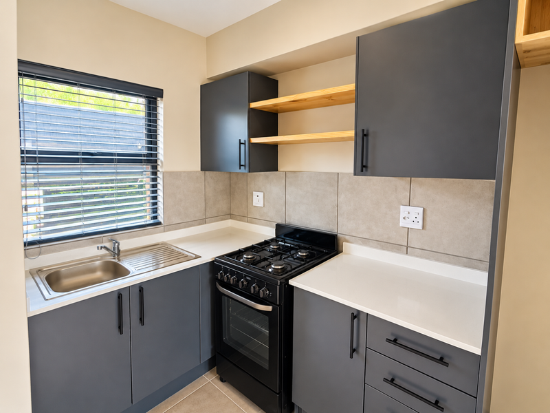 Modern kitchen featuring dark grey cabinetry, stone countertops, a stainless steel sink, and a built-in gas stove with oven.
