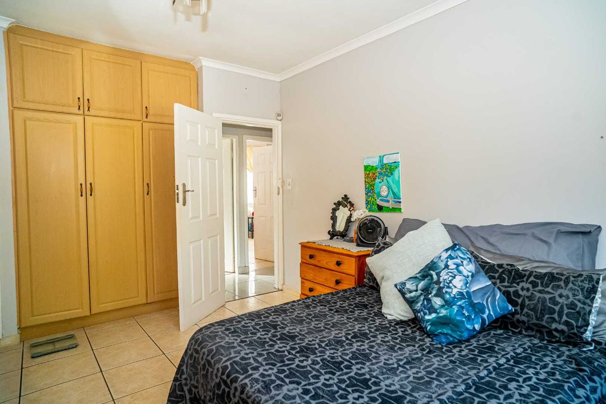 A bedroom featuring built-in wooden cabinetry and tiled flooring, providing functional storage space and direct access to the hallway.