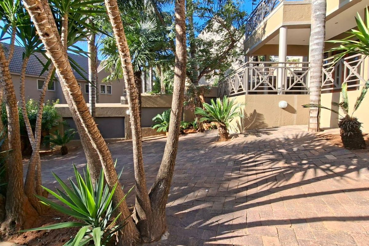 A private rear courtyard featuring paved flooring, established landscaping, and a raised patio area with a balustrade, providing a pleasant outdoor space.