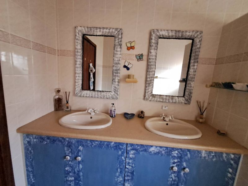 Bathroom featuring a double vanity with ceramic basins and tiled walls, offering potential for modernization through updated cabinetry and fixtures.