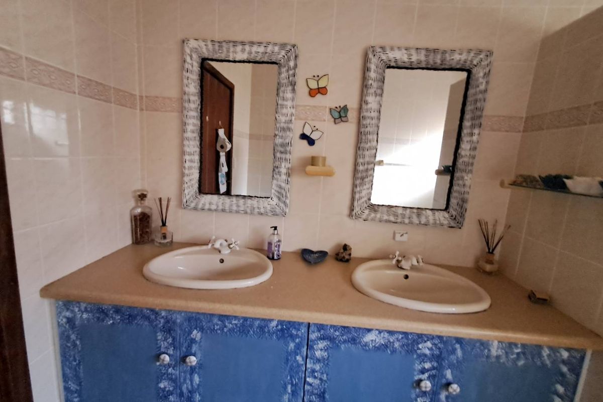 Bathroom featuring a double vanity with ceramic basins and tiled walls, offering potential for modernization through updated cabinetry and fixtures.