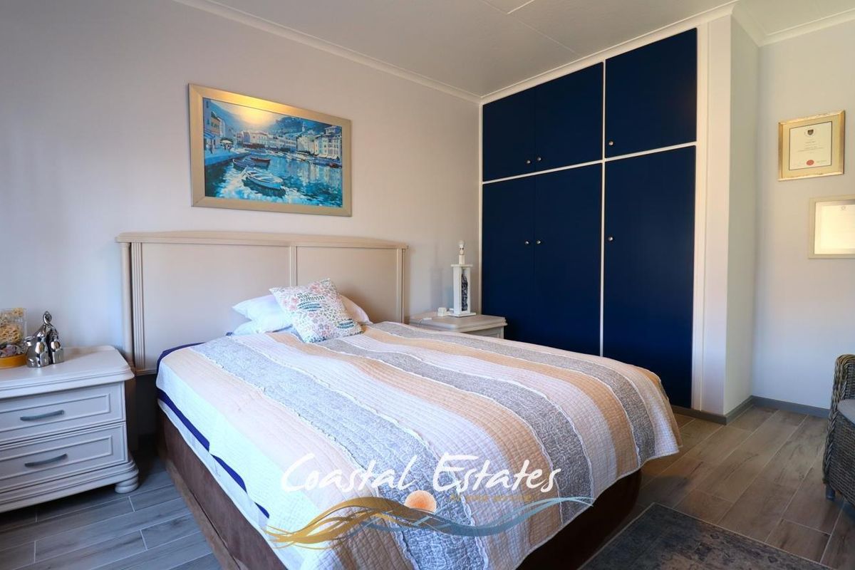 A well-maintained bedroom featuring built-in navy blue cabinetry and wood-look flooring.