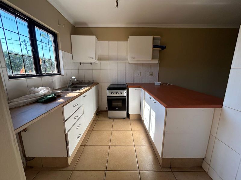 Functional kitchen featuring white cabinetry, laminate countertops, tiled backsplash, and a freestanding stove, offering a clean canvas for potential modern updates.
