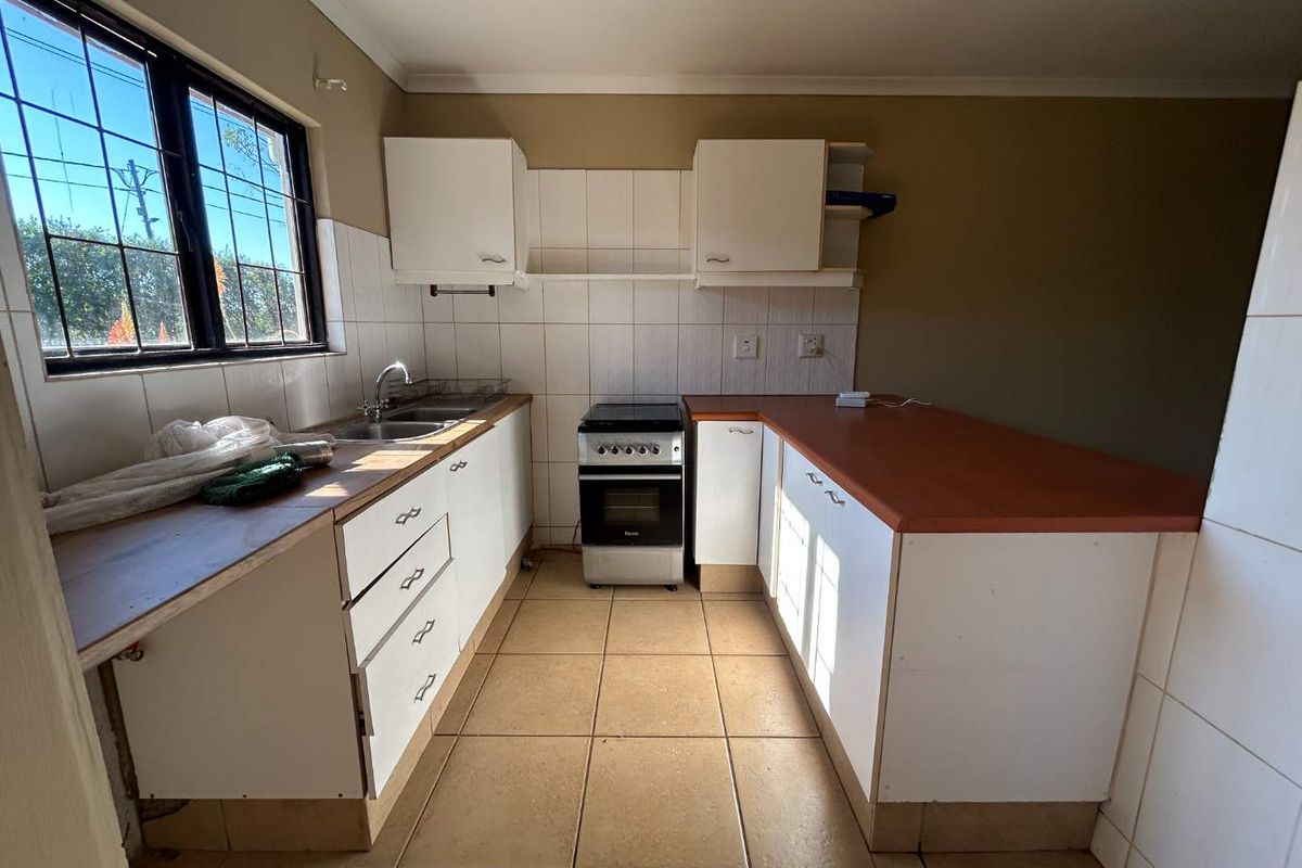 Functional kitchen featuring white cabinetry, laminate countertops, tiled backsplash, and a freestanding stove, offering a clean canvas for potential modern updates.