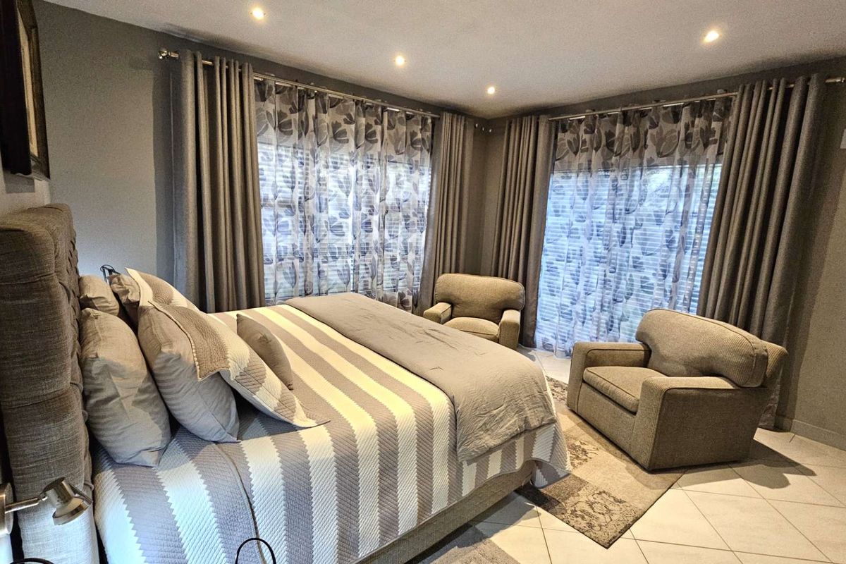 A well-maintained bedroom featuring tiled flooring, recessed ceiling lighting, and large sliding glass doors with integrated curtain tracks.