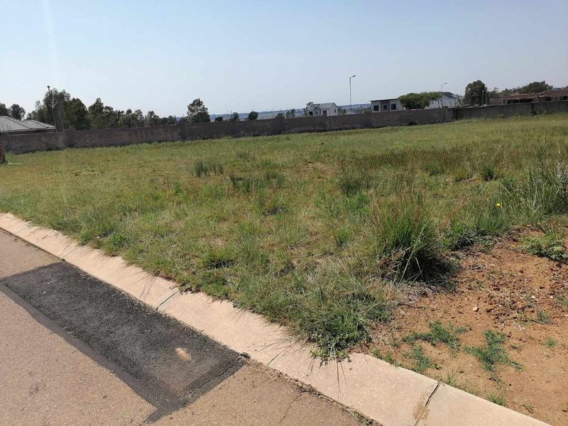 A vacant residential plot featuring a concrete curb and perimeter boundary wall, ready for development.