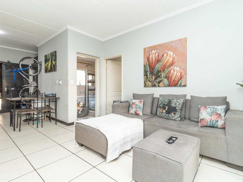 Open-plan living area featuring neutral tiled flooring and coved ceilings, providing a functional space with direct access to adjacent rooms.