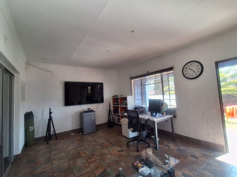 A living area featuring tiled flooring, recessed lighting, and large sliding glass doors providing access to the garden.