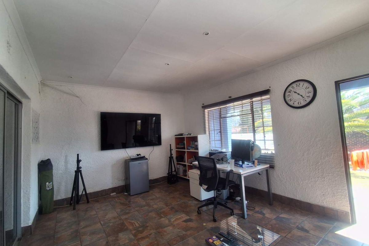 A living area featuring tiled flooring, recessed lighting, and large sliding glass doors providing access to the garden.