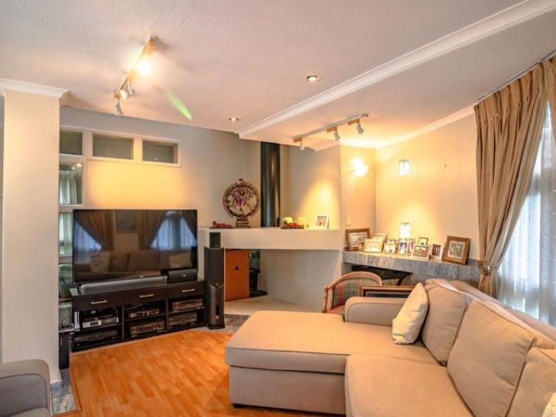 A comfortable living room featuring laminate flooring, a built-in fireplace, and a mix of recessed and track lighting.
