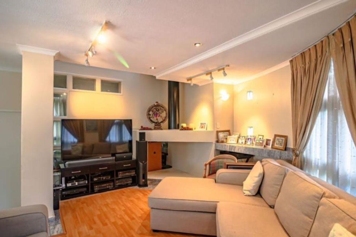 A comfortable living room featuring laminate flooring, a built-in fireplace, and a mix of recessed and track lighting.
