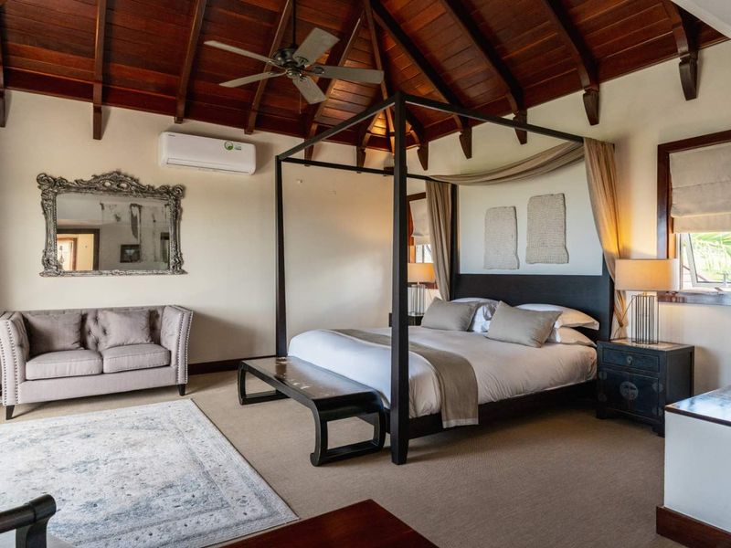 Spacious bedroom featuring a high vaulted timber ceiling, exposed beams, ceiling fan, and wall-mounted air conditioning unit.