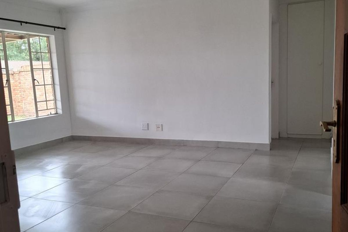 A bright, empty living area featuring neutral floor tiles, large windows, and a clean, minimalist aesthetic ready for personalization.
