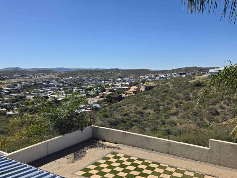 Elevated outdoor terrace featuring a unique checkerboard turf inlay and expansive panoramic views of the surrounding landscape and town.