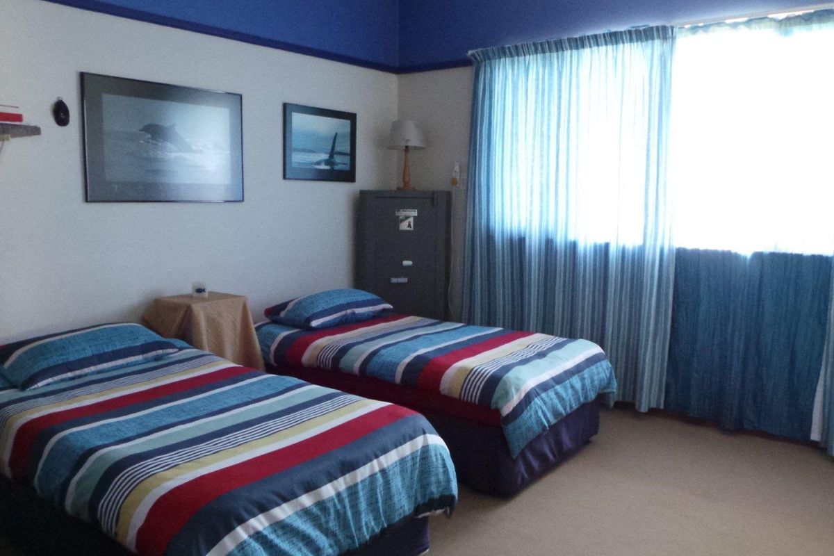 A bedroom featuring carpeted flooring, a large window with curtains, and a painted blue ceiling border.