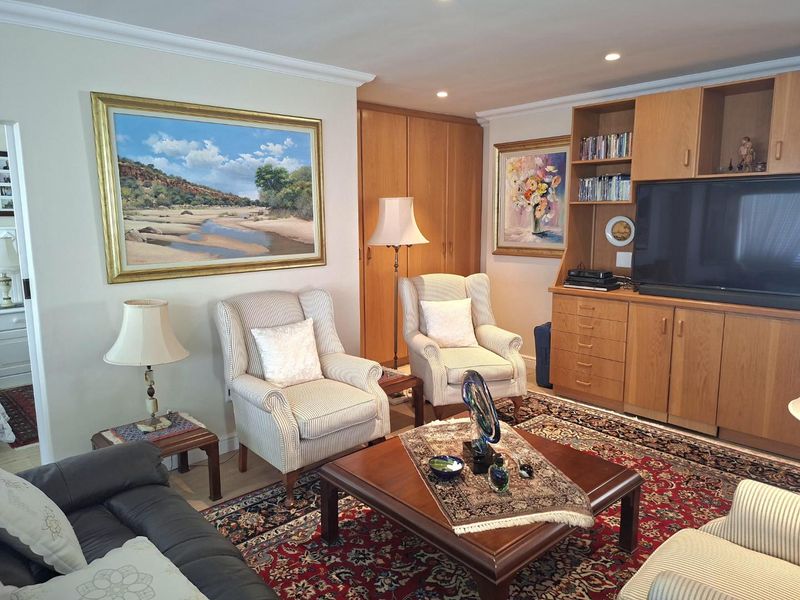 A comfortable living room featuring built-in wooden cabinetry, recessed ceiling lighting, and classic crown molding, providing a functional and well-maintained space.