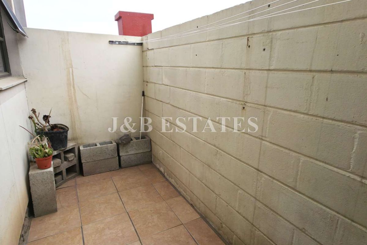 A small, enclosed outdoor utility or courtyard area featuring tiled flooring and masonry boundary walls.