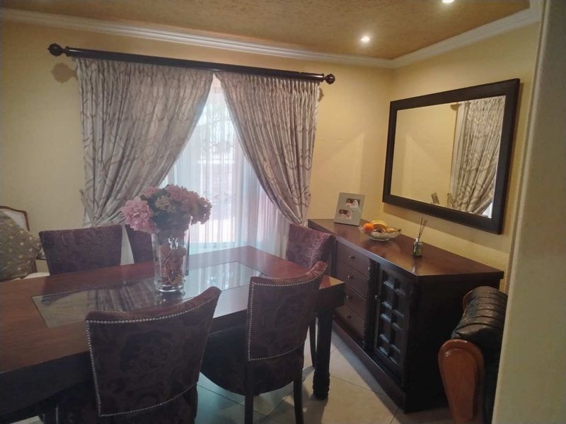 A dining room featuring tiled flooring, recessed downlights, and a coved ceiling, providing a functional space for family meals.