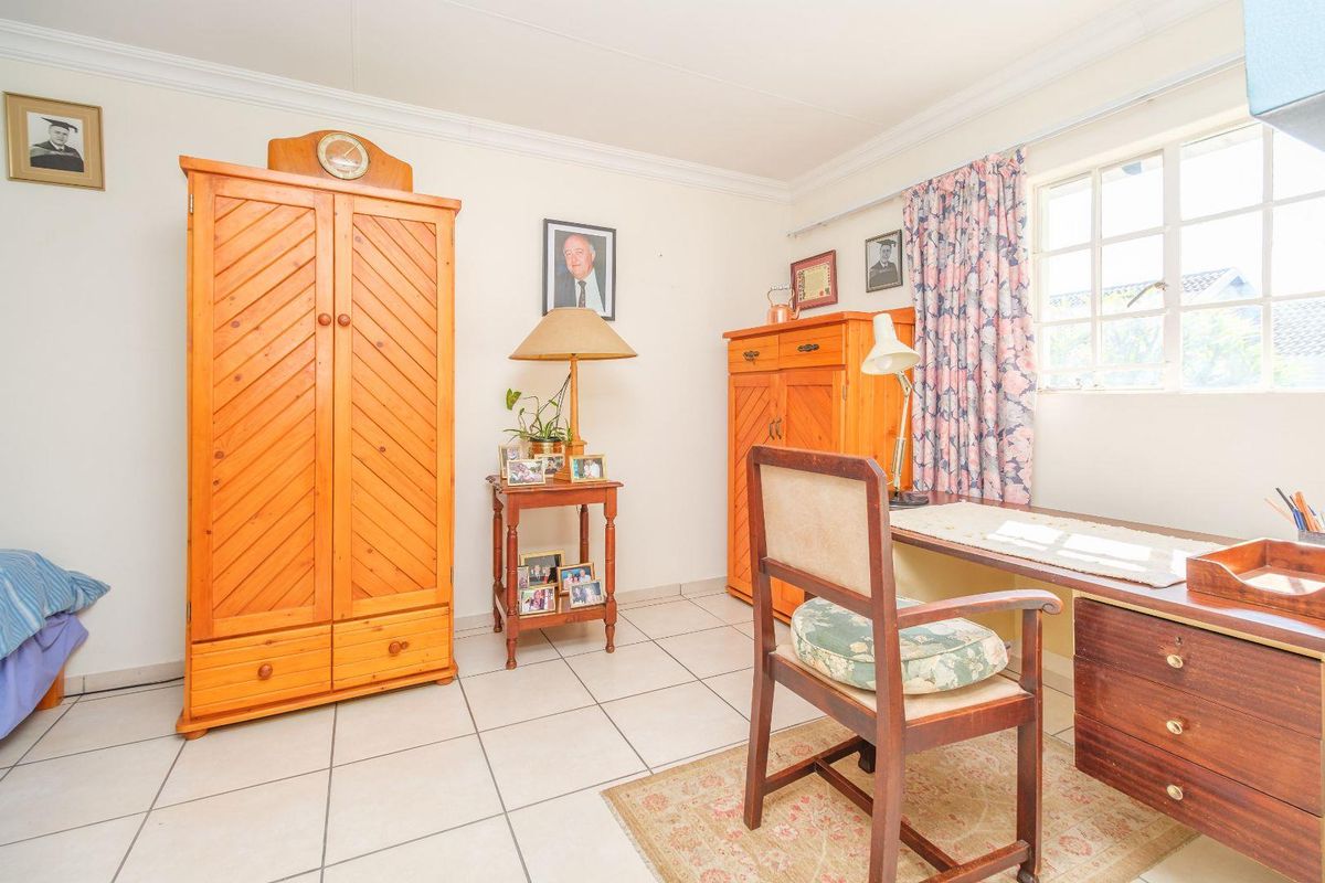 A functional bedroom featuring tiled flooring, coving, and a window, offering a neutral base for potential updates or restyling.