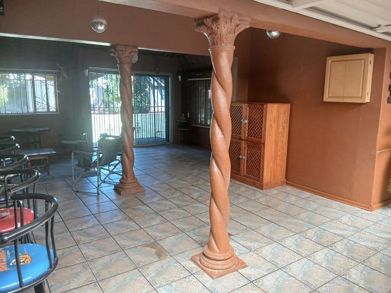 A covered patio area featuring decorative twisted columns, tiled flooring, and access to the garden through sliding glass doors.