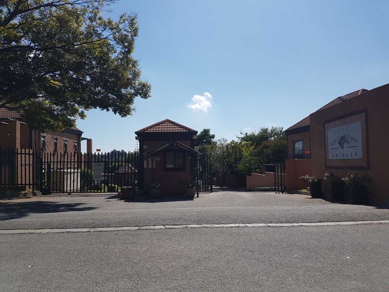The entrance to The Bridles complex, featuring a secure gated access point, guard house, and perimeter fencing.