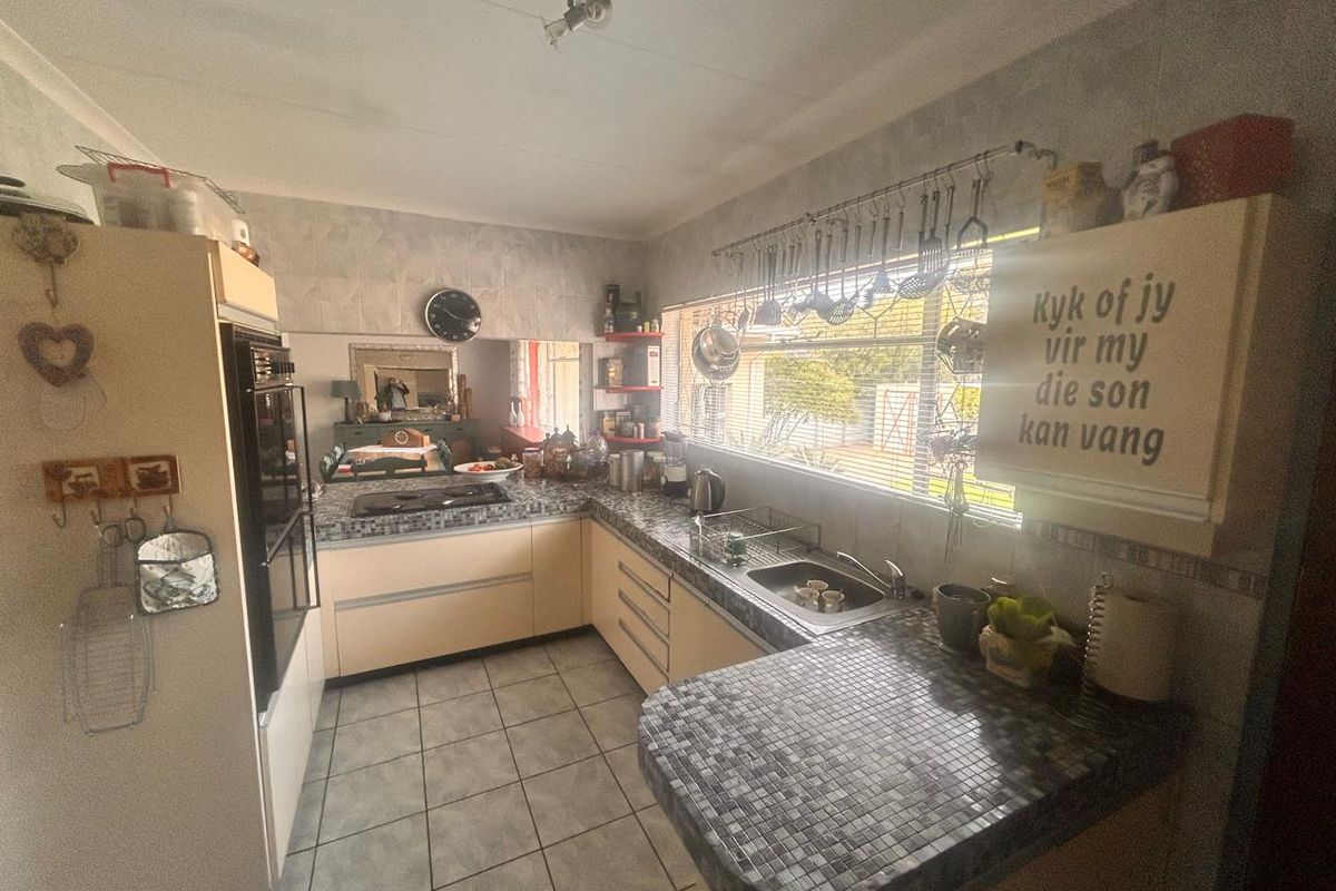 Functional kitchen featuring U-shaped layout, built-in oven, hob, and tiled countertops with ample natural light from the large window.