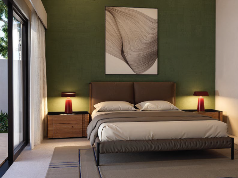 A modern bedroom featuring a textured green accent wall, large sliding glass doors providing access to an outdoor patio, and high-quality finishes.