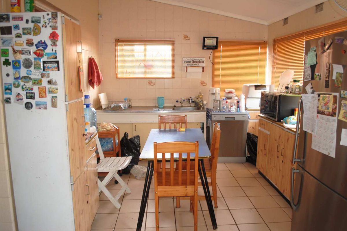 A functional kitchen space featuring wooden cabinetry, tiled splashbacks, and tiled flooring, offering a practical layout for daily meal preparation.