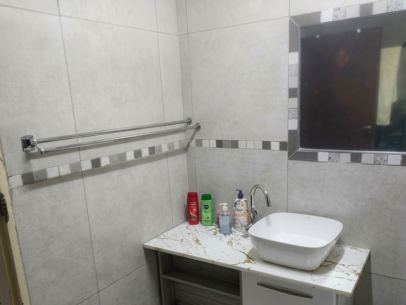 A modern bathroom featuring a vessel sink on a marble-effect vanity, tiled walls, and a wall-mounted mirror.