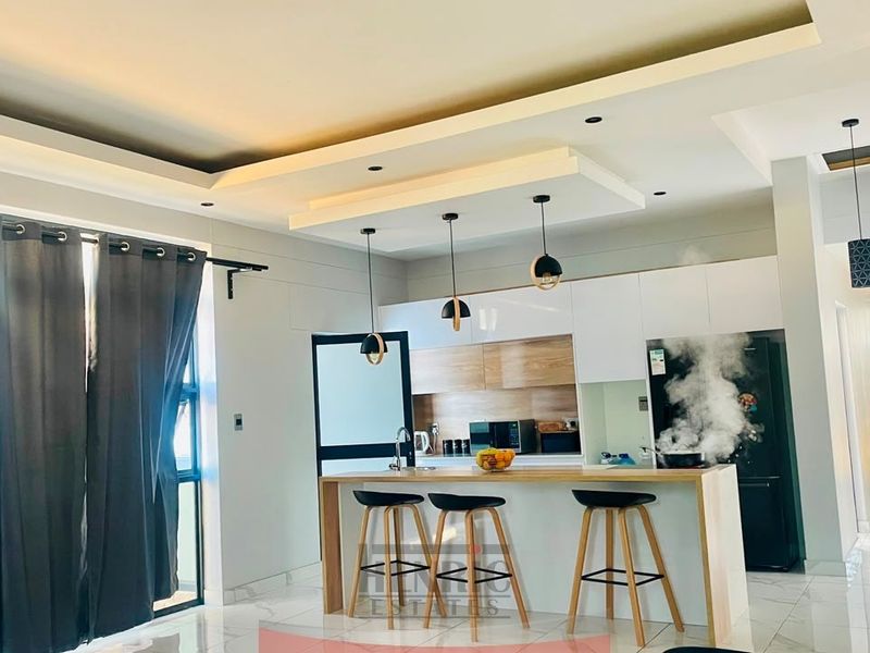 Modern open-plan kitchen featuring a central island, sleek cabinetry, and contemporary recessed ceiling lighting, creating a bright and functional living space.