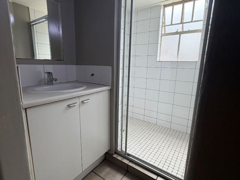 A functional bathroom featuring a vanity cabinet with basin, a separate shower enclosure with tiled finishes, and a window for natural light.