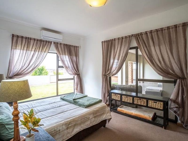 A well-lit bedroom featuring carpeted flooring, a split-system air conditioner, and large sliding glass doors providing access to an outdoor area.